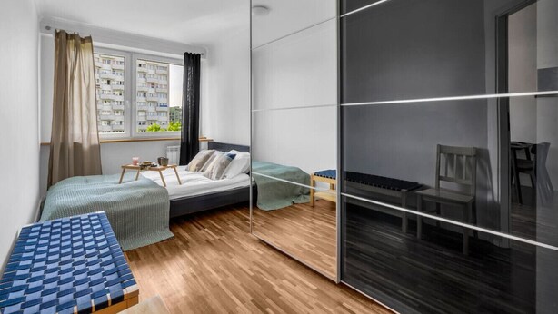 A modern bedroom with a bed, bedside table, and a large mirror.