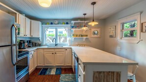 A modern kitchen with white cabinets, stainless steel appliances, and a large island. - Margaretaville (Key West)