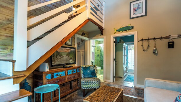 A spacious living area with a wooden staircase, a comfortable sofa, a patterned armchair, and a coffee table. - Margaretaville (Key West)