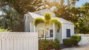 A small, single-story house with a white exterior, a front porch, and a mailbox. - Margaretaville (Key West)