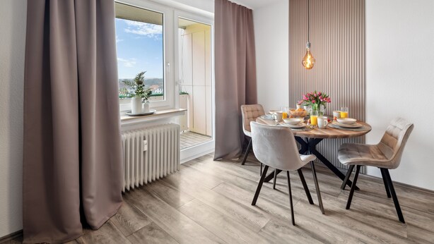 Un'area pranzo con tavolo apparecchiato per quattro persone, un termosifone e vista sull'esterno.