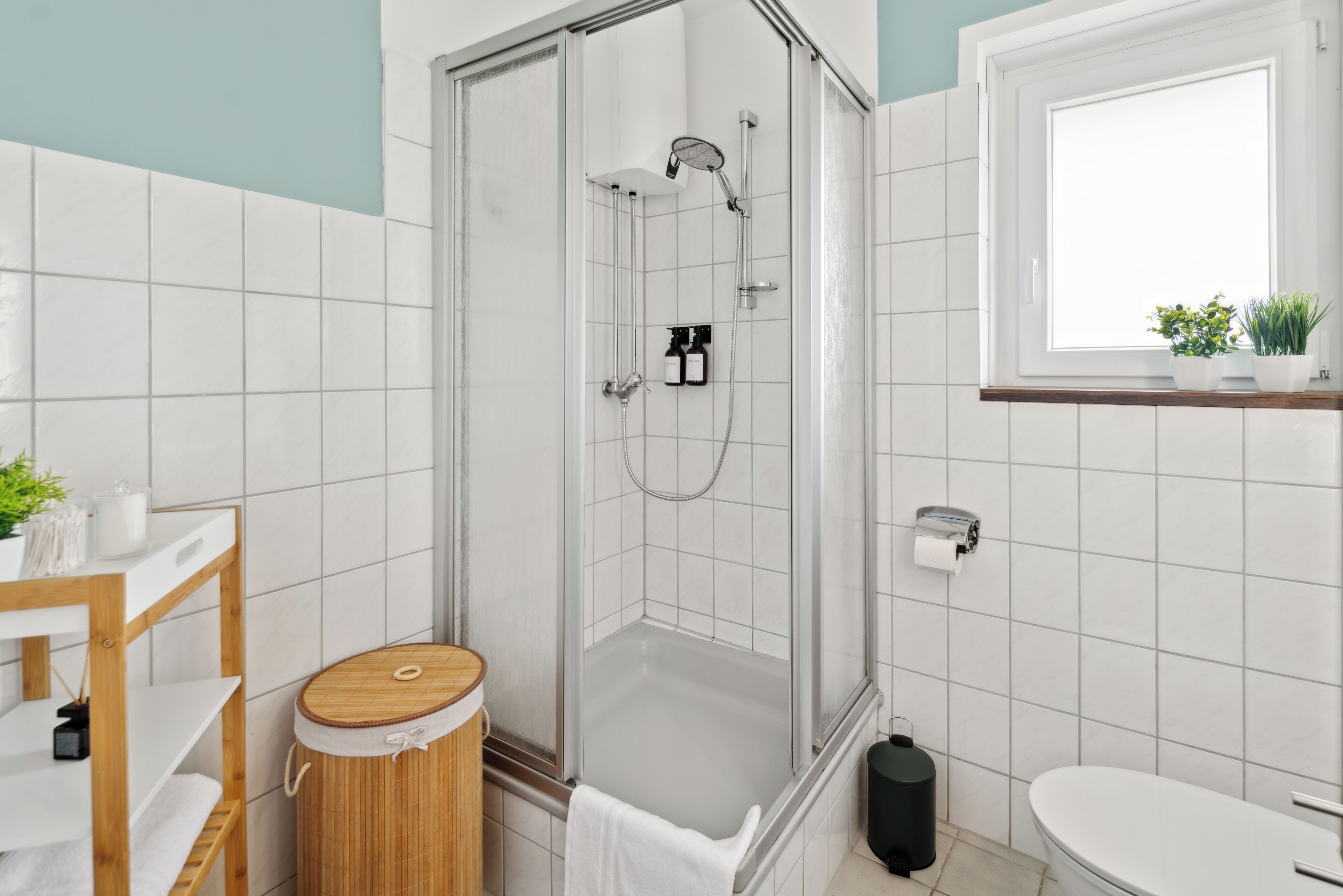 A modern bathroom with a glass-enclosed shower, a wooden vanity, and a toilet.