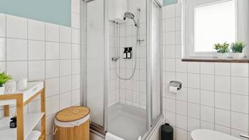 A modern bathroom with a glass-enclosed shower, a wooden vanity, and a toilet.