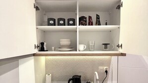 A compact kitchenette with a countertop, a kettle, a coffee maker, and storage shelves. - The Vinci Residence • Premium Studio | Kraków Old Town (Kraków)