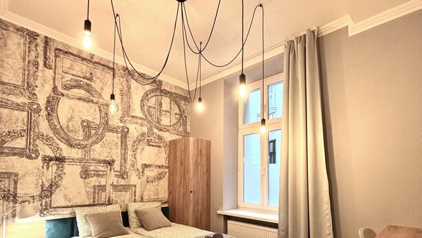 A bedroom with a large bed, a wooden desk, and a window with curtains. - The Vinci Residence • Premium Studio | Kraków Old Town (Kraków)