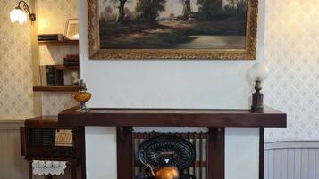 Una stanza con un camino, un quadro sopra e una radio d'epoca su un supporto in legno.
