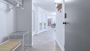 A hallway with a metal rack, a white door, and a view into a room with a desk and shelves. - Cozy & Spacious 2BR at Stampede w/ Parking, AC (Calgary)