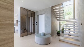 Ein modernes Interieur mit einer runden Sitzecke, einem Glastreppenaufzug und einer Treppe mit Ausblick.
