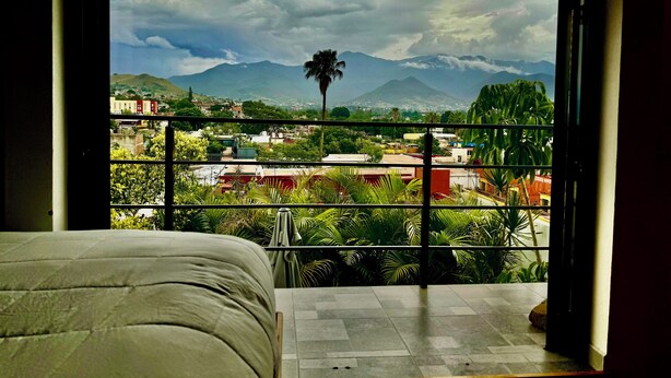 A balcony with a view of a cityscape, mountains, and a palm tree. - EL MIRADOR, Casa EA Oaxaca, Historic Center, Terrace and Mountain View. (OAXACA DE JUAREZ)