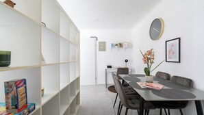 Un espace repas moderne avec une longue table, des chaises et une horloge au mur.