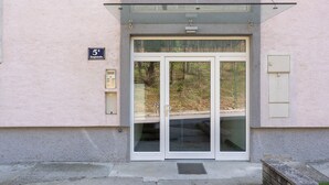 Une entrée d’immeuble dotée d’un auvent en verre, d’une porte avec un panneau de verre et d’un petit panneau indiquant l’adresse.