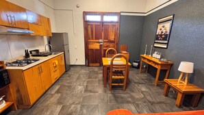 Uma cozinha compacta com armários de madeira, fogão a gás e um espaço de refeições com mesa e cadeiras.