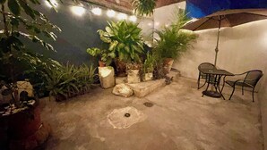 Um espaço de pátio ao ar livre com plantas em vasos, uma mesa e cadeiras.