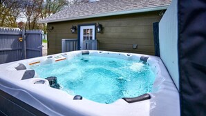 Een hottub in een buitengebied met een houten huis op de achtergrond.