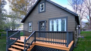 Een tweelaags huis met een houten terras en een zwarte balustrade.