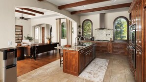 A spacious kitchen with wooden beams, a large island, and a view of the outdoors.