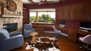 A modern living room with a stone fireplace, a large window with a view, and a cozy seating area.