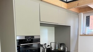 Une cuisine moderne dotée d’un four encastré, d’une plaque de cuisson et d’un plan de travail agrémenté de divers ustensiles de cuisine.
