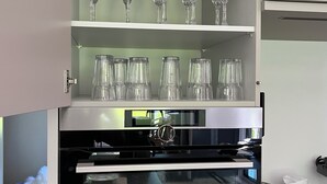 Un meuble de cuisine doté d’étagères où sont rangés différents types de verrerie, notamment des verres à vin et des verres à cocktail.