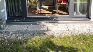Une cuisine moderne dotée d’un îlot central, d’un coin repas avec deux chaises et d’une grande fenêtre donnant sur un jardin.