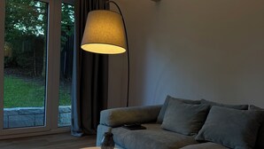 Un salon moderne avec un canapé gris, une table basse ronde et un lampadaire.