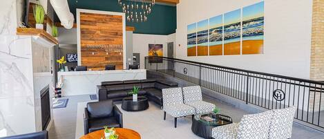 Un vestíbulo de hotel con una recepción, zona de estar y un gran mural de una playa.