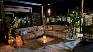 Un espace extérieur moderne aménagé avec un canapé, une table et un éclairage décoratif.
