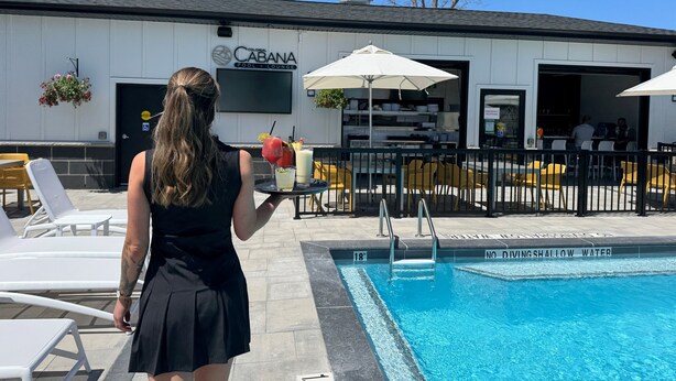 Un área de piscina con sillas de descanso, un cartel que indica agua poco profunda y un edificio con señalización de piscina y sillas de descanso.