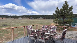 Eine Terrasse mit Gartenmöbeln mit Blick auf eine Wiese und einen Wald.