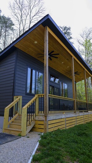A cabin with a wooden deck, a covered porch, and a staircase leading to the entrance.
