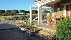 A poolside area with a pergola, outdoor seating, and a view of the surrounding landscape.