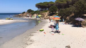 A beach with people sunbathing, umbrellas, and kayaks.