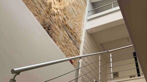 A staircase with wooden steps and metal railings, leading to a lower level with a textured wall and a skylight above. - House in the heart of a village (Sainte-Foy-la-Grande)