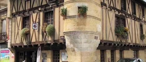 A historic building with a central tower, a traditional facade with timber framing, and a street-level entrance.