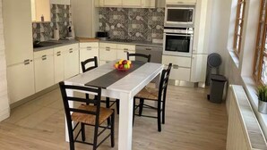 A modern kitchen with white cabinets, a central island, and a microwave. - House in the heart of a village (Sainte-Foy-la-Grande)
