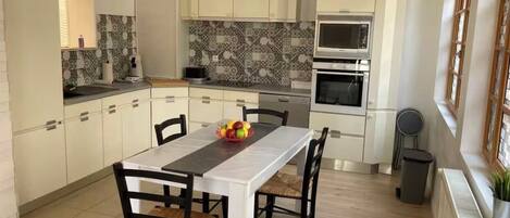 Una cocina moderna con armarios blancos, una isla central y un microondas.