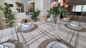 Un coin repas avec une nappe à carreaux, des assiettes blanches et un vase de fleurs.