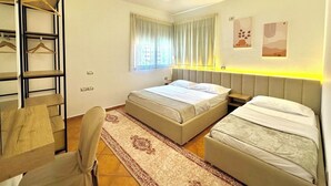 A bedroom with a bed, a chair, a desk, a wardrobe, and a window with curtains. - Seaside and spacious Apartment for up to 7 people (Vlorë)