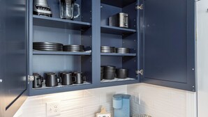Una cocina con armarios azul oscuro, electrodomésticos de acero inoxidable y una estación de café.
