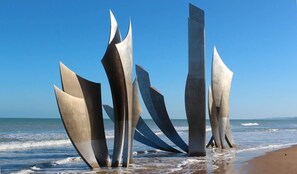 Eine Skulptureninstallation am Strand mit abstrakten Metallkonstruktionen.