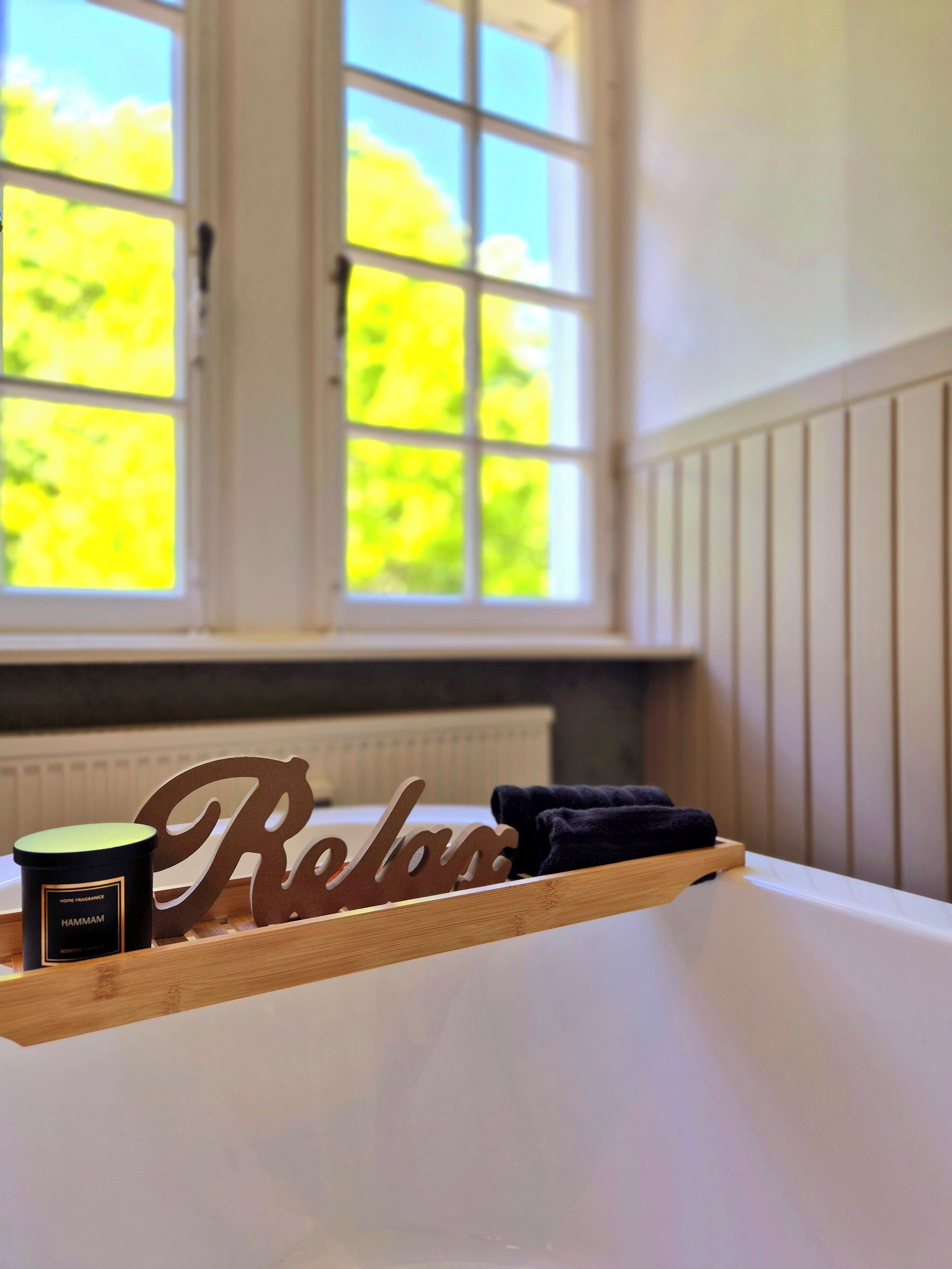 Una estantería de madera con un recipiente negro que dice "Hammam" y una señal de madera con la palabra "Relájate".
