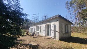 Een laag, rechthoekig gebouw met een plat dak, witte buitenmuren en een veranda met twee stoelen.