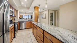 A modern kitchen with stainless steel appliances, wooden cabinets, and a marble countertop.