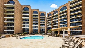 A hotel with multiple floors, outdoor pool, and sun loungers.