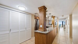 A kitchen with a wooden island, white cabinets, a stainless steel refrigerator, and a tiled floor.
