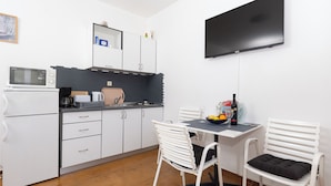 A compact kitchen with white cabinets, a microwave, a coffee maker, and a TV mounted on the wall. - Apartments Doko Zaton Bay (Zaton)