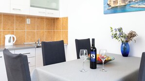 A dining area with a table set for two, a wine bottle, and a vase with flowers. - Apartments Doko Zaton Bay (Zaton)