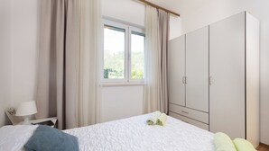 A hotel room with a bed, a nightstand, a wardrobe, and a window with curtains. - Apartments Doko Zaton Bay (Zaton)