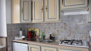 A kitchen with light-colored cabinets, a gas stove, a dishwasher, and a tiled backsplash. - Gite des Bords de rance (Pleudihen-sur-Rance)