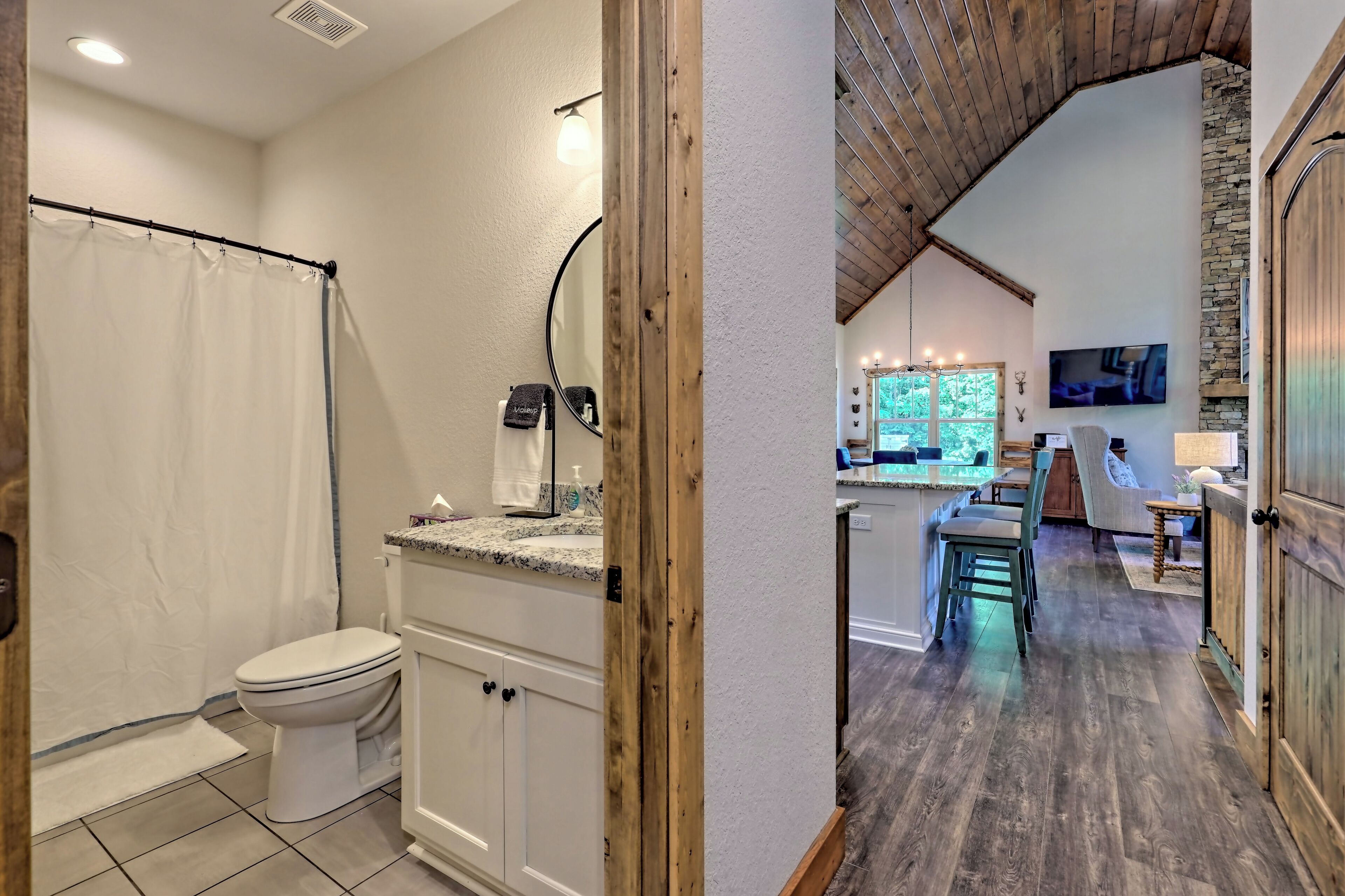 A bathroom with a toilet, shower curtain, and a vanity with a mirror.